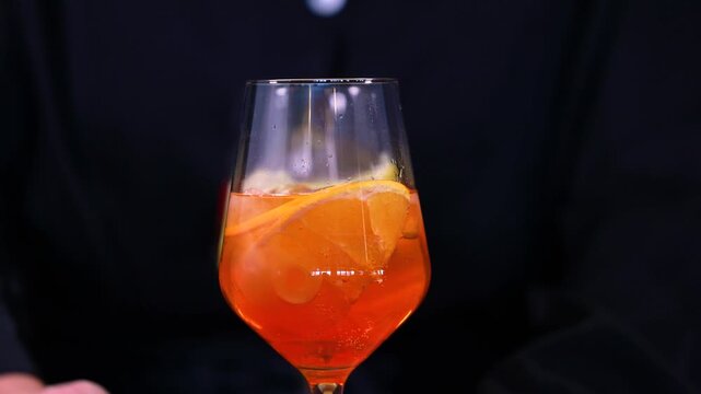 Bartender revealing three colorful citrus cocktails on wooden bar counter in elegant sparkling stem glasses