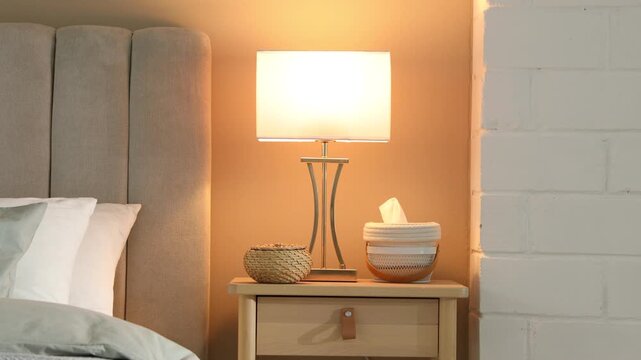 Woman taking book out of bedside table drawer after lamp turning on at home