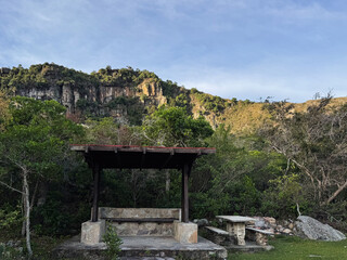 Rustic stone gazebo and picnic area with a picturesque mountain cliff backdrop during Golden Hour