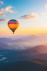 Fototapeta premium Hot air balloon floats over misty mountains at sunrise