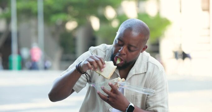 African American man in short-sleeve shirt opening clamshell container, lifting sandwich to eat