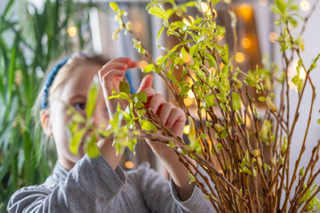 child, girl Young nature explorer discovering new leaves on branches, Child's hand touching green buds, representing connection with nature, Spring educational activity