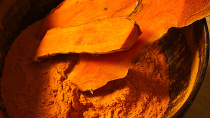 Turmeric powder and turmeric rhizomes in a bowl