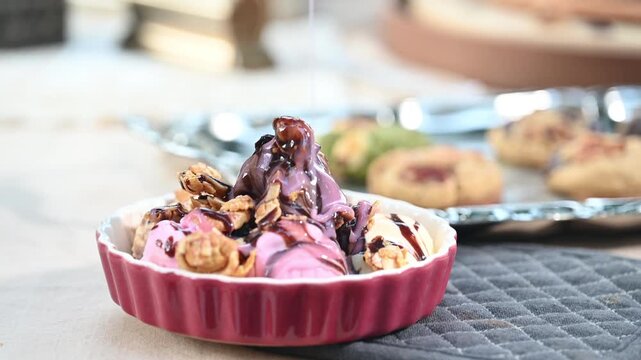 Dessert ice cream chocolate sauce drizzle pink bowl nut granola ceramic closeup, creamy scoop under rich flow in ramekin and fluted dish, cozy kitchen table scene, sundae vibe, gentle light