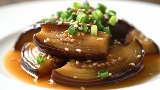 Macro shot of glossy Japanese braised eggplant (Nasu Nimono) topped with green onions and sesame seeds, resting in sweet soy sauce, representing traditional Asian vegetarian food.