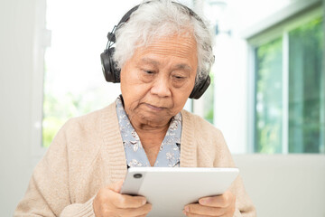 Asian senior woman patient happy to use earphone to listen relax music.