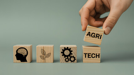Hand placing a wooden block with agi text on top of blocks symbolizing technology and innovation.