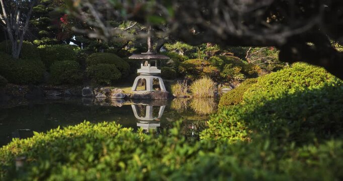 Beautiful old stone Japanese lantern reflection in pond of park