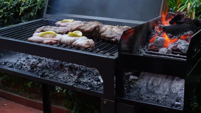 Carne as&aacute;ndose en parrilla con brasas y carb&oacute;n encendido al aire libre