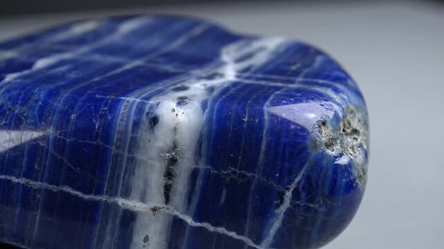 A close-up view of a polished blue stone with white veins, reflecting light