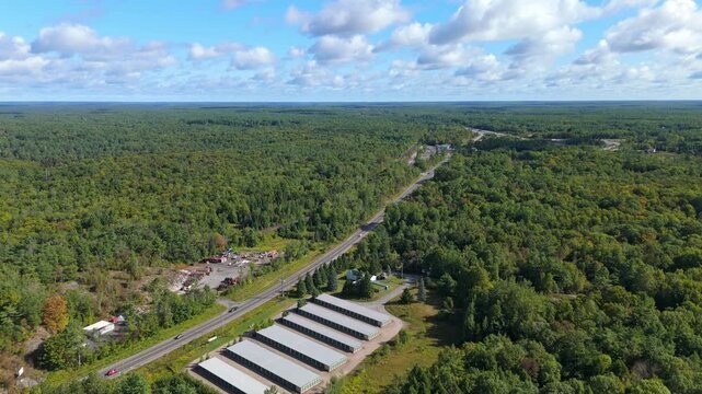 Aerial drone view of industrial buildings surrounded by dense forest near Gravenhurst in Muskoka, cottage country region, showing rural industry, roadway access and natural landscape