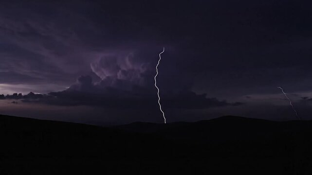 Dramatic lightning strikes illuminate dark mountain silhouettes during a storm.