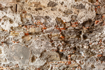 Decaying stone and brick walls of a pedestrian underpass underneath a road in Genoa, Italy