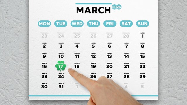 Close-up of a male hand pointing finger at the date of St. Patrick's Day 2026 on a wall calendar