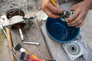 Man using hand tools to fix mechanical components of a washer.