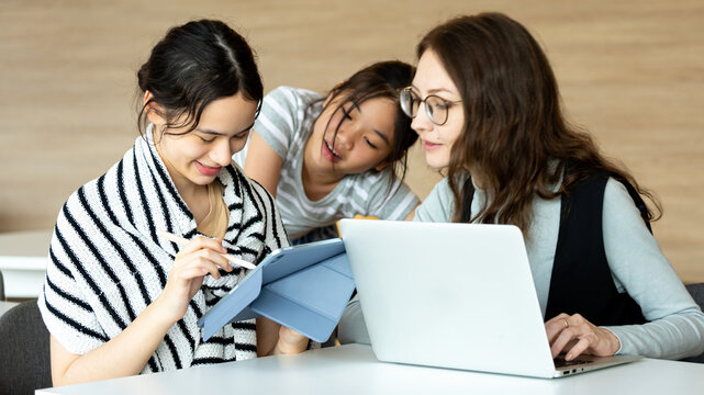 Multiracial female students studying together with laptop and tablet in modern classroom, collaborative learning, digital education, teamwork, technology in school, young women working on project