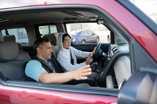 Parent teaching driving safety and braking to his adolescent son.