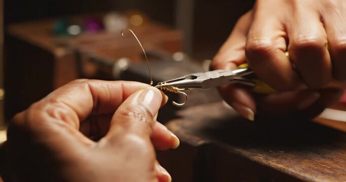 Close-up of hands using pliers to manipulate wire for crafting jewelry in a workshop setting
