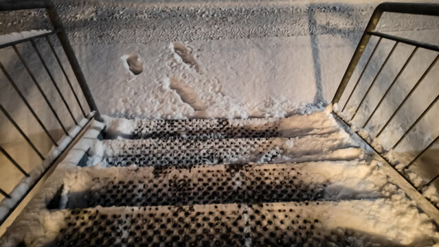 Stairway to snowy ground. Steps covered in snow in winter in the night.