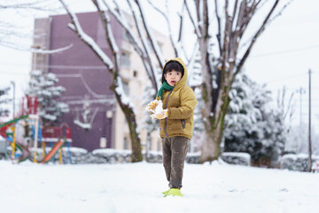 雪の公園で遊ぶ6歳の男の子