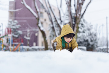 雪の公園で遊ぶ6歳の男の子