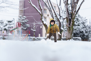 雪の公園で遊ぶ6歳の男の子