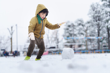 雪の公園で遊ぶ6歳の男の子
