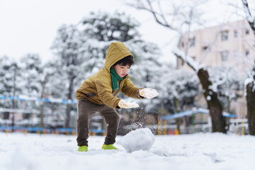 雪の公園で遊ぶ6歳の男の子