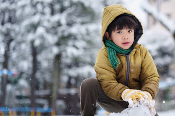 雪の公園で遊ぶ6歳の男の子
