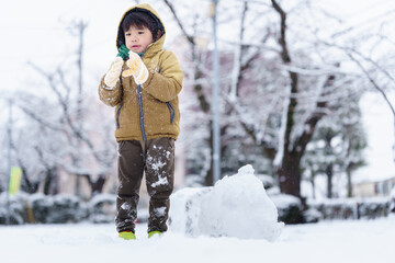 雪の公園で遊ぶ6歳の男の子