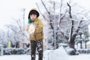 雪の公園で遊ぶ6歳の男の子