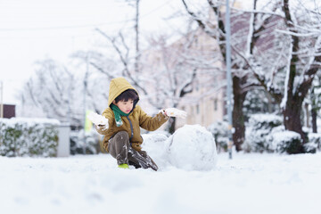 雪の公園で遊ぶ6歳の男の子