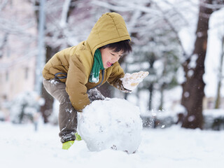 雪の公園で遊ぶ6歳の男の子