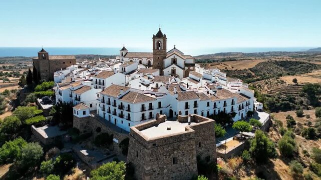 Aerial view of a charming Spanish village with white houses, brown rooftops, and a church tower