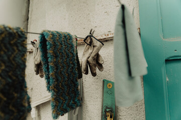 Gants de travail suspendus sur un fil à linge devant une façade turquoise © Pablo