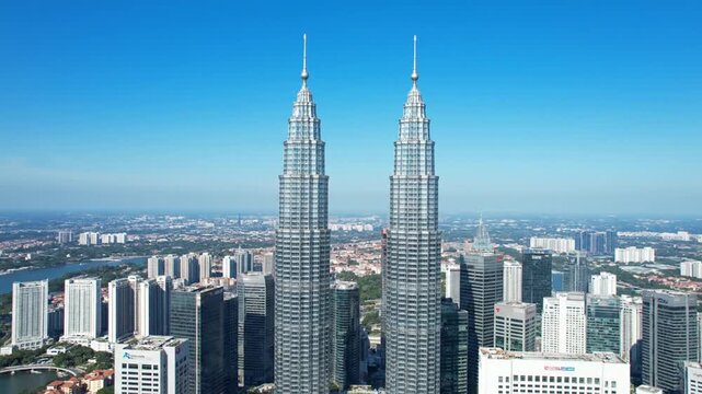 Aerial view of twin skyscrapers piercing a clear, blue sky, surrounded by other city buildings