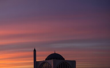 Obraz premium A serene mosque silhouette against a vibrant purple and orange sunset sky