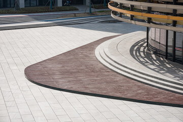 Modern plaza with curved walkway and architectural shadows on paved ground © zhu difeng
