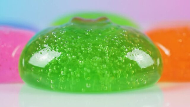Vibrant pink and green slime expands and contracts with many bubbles.