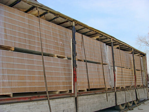 Cargo trailer carrying insulated sandwich panels for warehouse construction is transporting them from machine to construction site