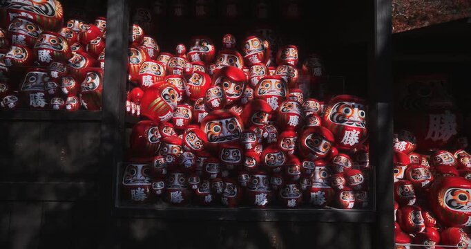 Steady cam, slow motion, low shot on cluster of daruma dolls in wooden structure