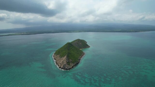 Aerial view of the turquoise sea and ilheu das cabras with S&atilde;o Tome coast at background. Circular drone shot.Africa