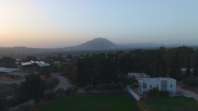 Kfar Kish village in Israel offers a panoramic view of the misty Mount Tabor during a winter evening.
