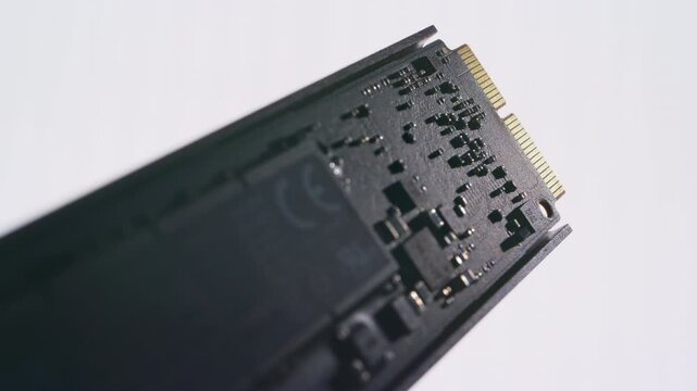 Cinematic macro shot of a dark SSD component with white background.