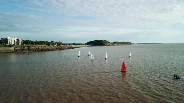 A drone shot of small sailing boats bobbing in front of the Clevedon Uk coast. The sky is blue with white clouds