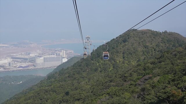 Aerial View of Ngong Ping 360 Cable Car Descending Over Lush Mountains with Hong Kong International Airport Background