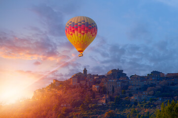 Hot air balloon flying over Eze village is a famous tourist destination on French Riviera at sunset - Nice, France