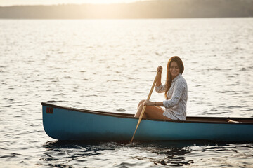 Boat, rowing and smile with woman on lake for adventure, hobby or travel in nature environment. Paddle, relax and sunset with happy person in canoe on water with space, summer holiday or vacation