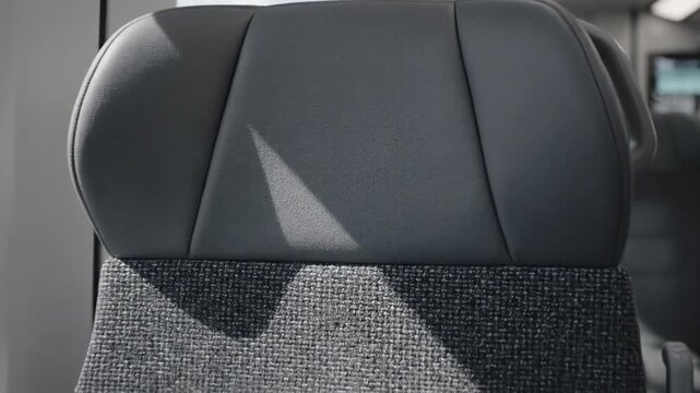 Interior shot of train seats, capturing gray upholstered headrests and a textured fabric base