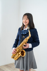Naklejka premium アルトサックスを持って笑顔の制服姿の日本人少女
